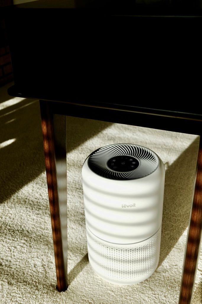 White Levoit air purifier situated under table in room with carpet
